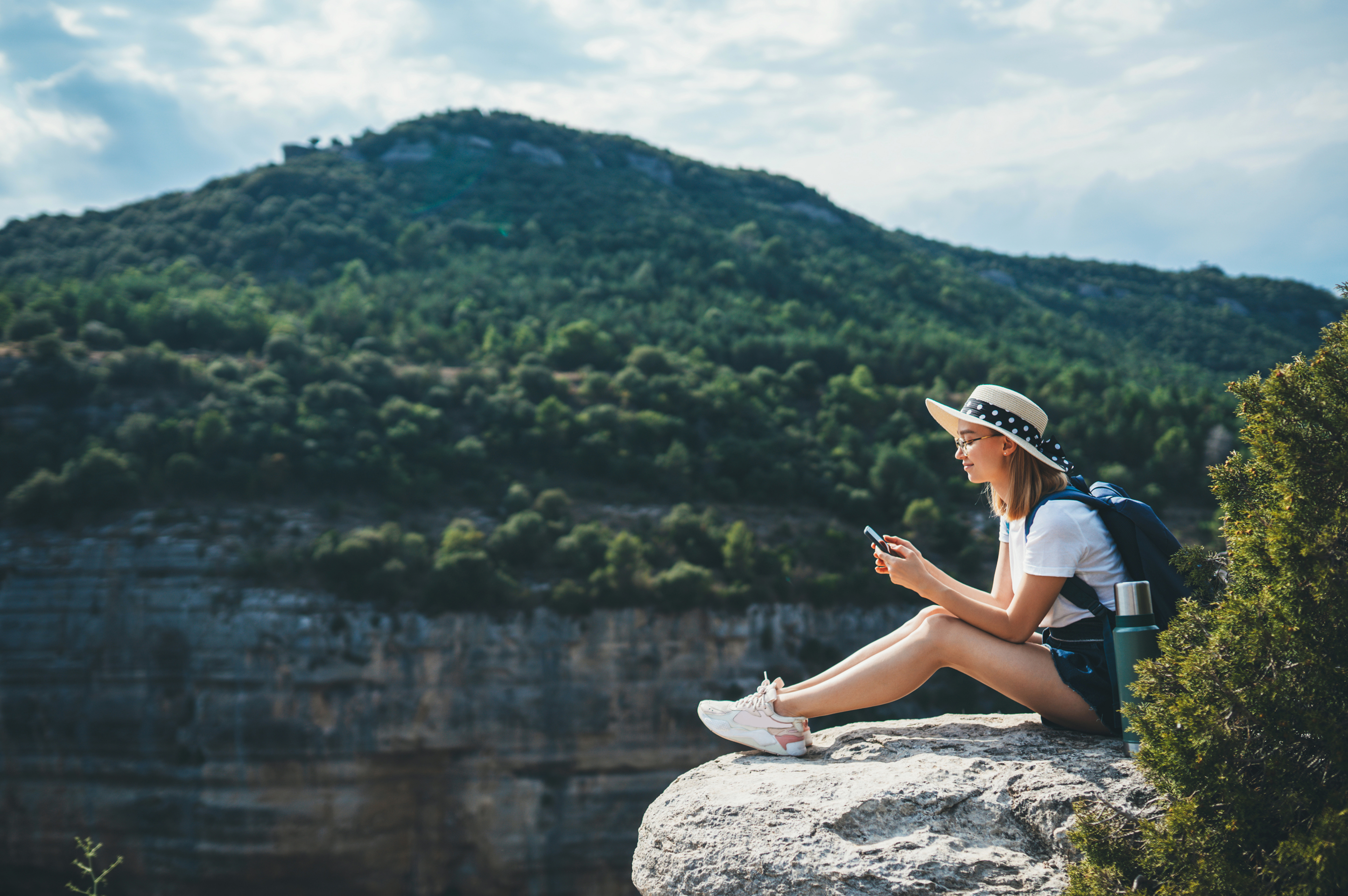 Traveler using the Voyajoy app on a phone overlooking a scenic valley